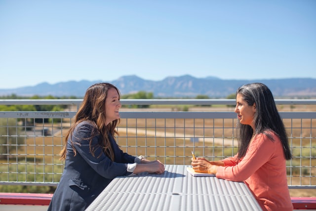 two business women sitting outside with a view of mountains